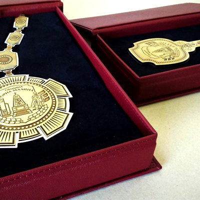 Две отворени бордо кутии със златни награди. Вляво: голям медал/верига. Вдясно: декоративен ключ. И двете имат надпис Горна Малина.