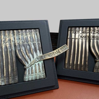 Два броя кожени рамки за плакет на ДКТ Иван Димов - Хасково от черна еко кожа. Месингова отливка с патина, която изобразява полу отворена завеса на сцена.