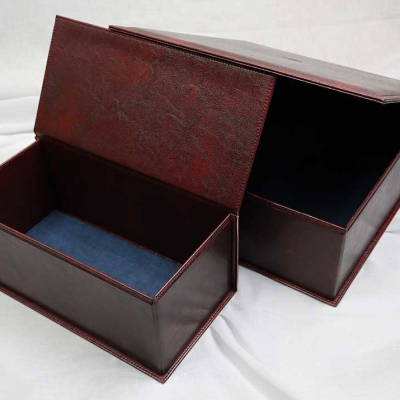 Две отворени правоъгълни кутии от тъмночервена набръчкана кожа със синьо кадифе.