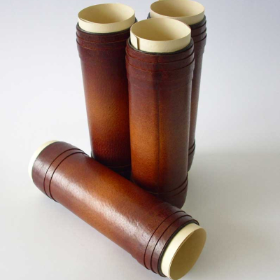 Четири кафяви кожени тубуса/калъфа със светла вътрешност. Един лежи хоризонтално отпред, три са изправени отзад.